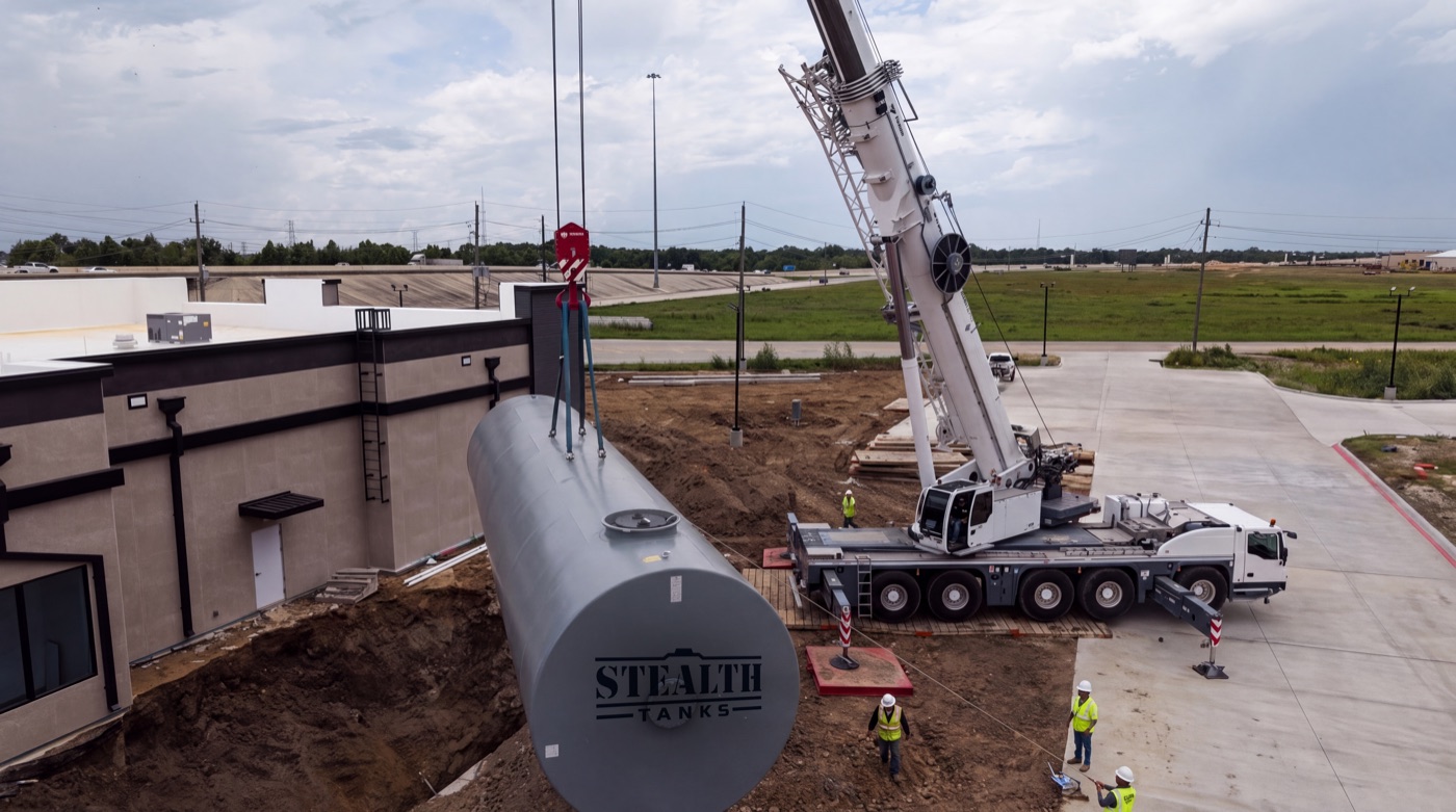 A compartmented underground storage tank being set into a prepared excavation