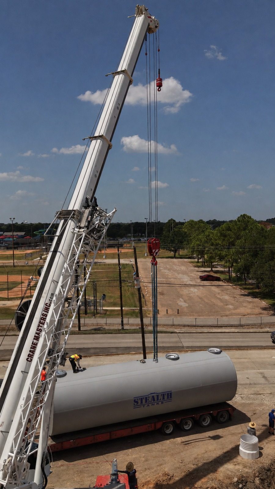 Crane lifting a double-wall underground storage tank into position on a Pasadena, Texas job site